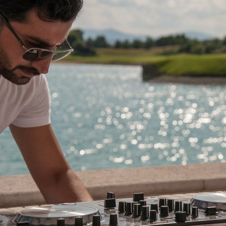 DJ mit Dj-Pult, im Hintergrund ´Wasser eines Sees